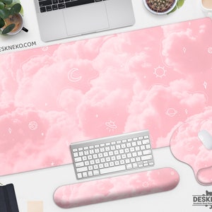 May include: A pink desk mat, mousepad, and wrist rest set with a cloud and celestial design. The set includes a large desk mat, a mousepad, and a wrist rest, all featuring a pink cloud pattern with white celestial icons.