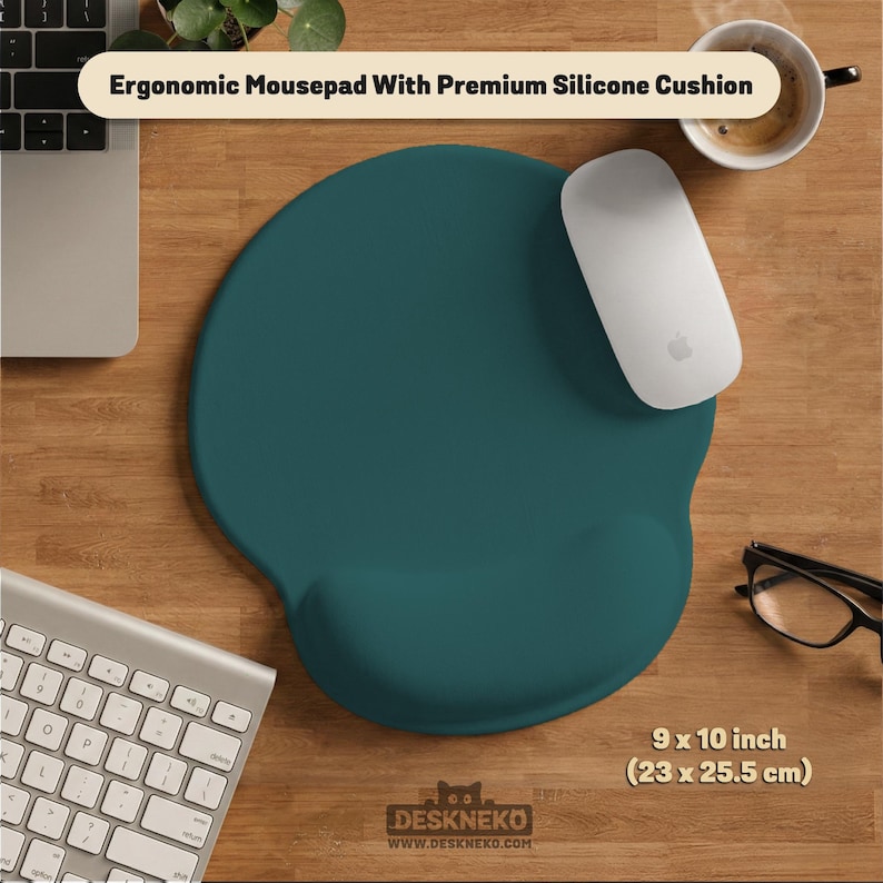 Op de afbeelding: Teal ergonomische muismat met een premium siliconen kussen, 23 x 25,5 cm. De muismat heeft een ingebouwde polssteun. Een witte muis en toetsenbord zijn ook zichtbaar. De tekst "Ergonomic Mousepad With Premium Silicone Cushion" wordt weergegeven.