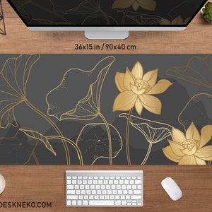 May include: A rectangular desk mat with a dark gray background and gold lotus flower design. The mat measures 36 x 15 inches. The flowers and leaves are outlined in gold. The website address www.deskneko.com is printed at the bottom.