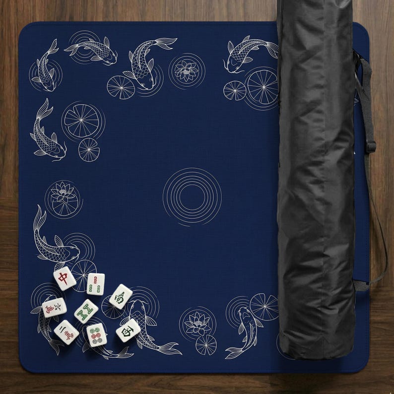 Puede incluir: Un tapete de Mahjong azul marino con un dise&ntilde;o de peces koi y nen&uacute;fares. El tapete incluye un juego de fichas de Mahjong y una funda de transporte negra. El tapete est&aacute; enrollado y listo para jugar.