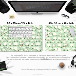 May include: Two rectangular desk mats, 24 x 14 inches and 18 x 14 inches, feature a repeating pattern of cartoon frogs in shades of green and white. A keyboard and mouse are placed on the larger mat. The text "DeskNeko" and website address are visible.