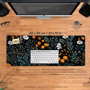 May include: A black desk mat with a floral pattern featuring white, orange, and teal flowers and foliage. The mat measures 31 x 12 inches. A white keyboard sits on the mat. The text "DeskNeko" and "www.DESKNEKO.COM" are visible.
