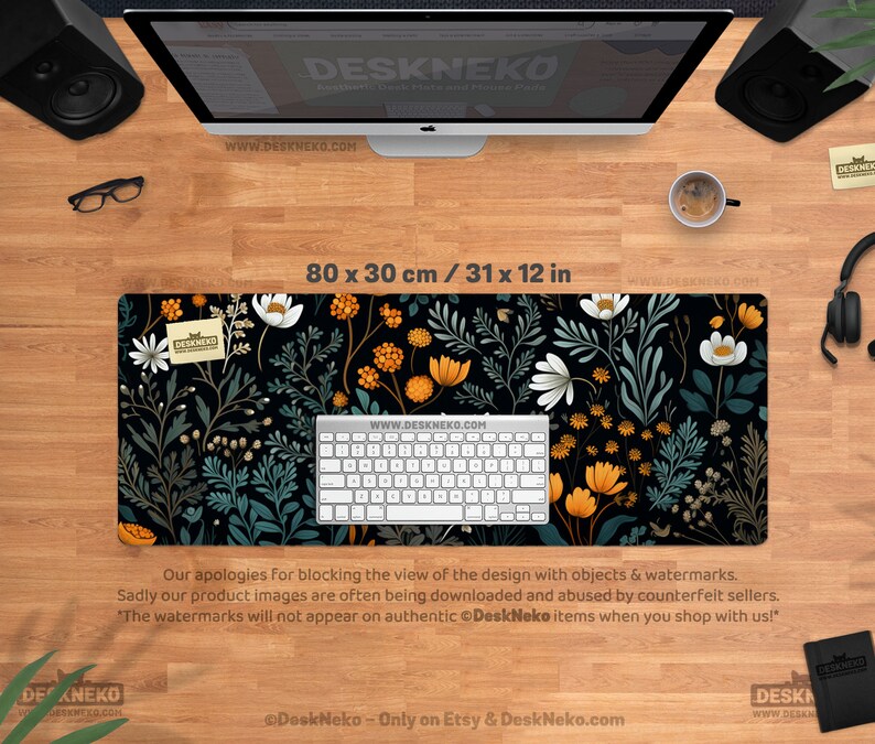 May include: A black desk mat with a floral pattern featuring white, orange, and teal flowers and foliage. The mat measures 31 x 12 inches. A white keyboard sits on the mat. The text "DeskNeko" and "www.DESKNEKO.COM" are visible.