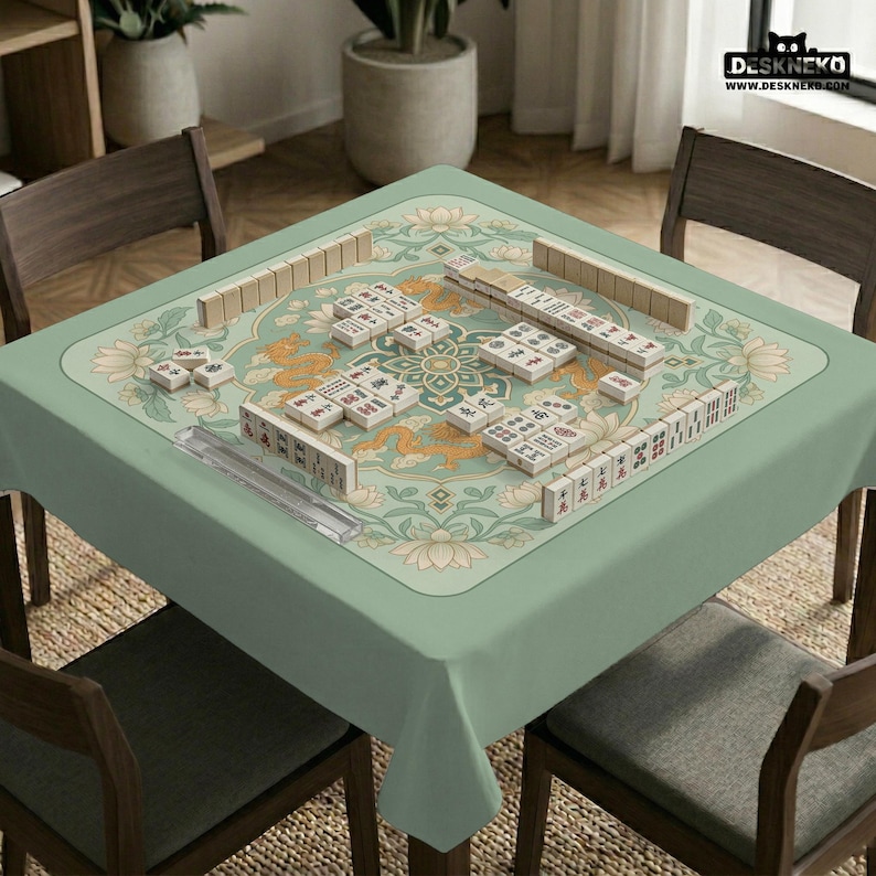 May include: A square, light green Mahjong table with a floral and dragon design. The table is set with tiles, racks, and a clear plastic dice holder. The table is surrounded by four wooden chairs.