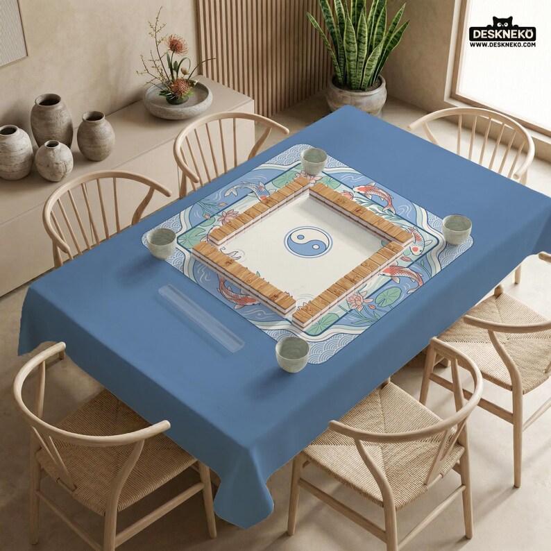 May include: A blue tablecloth with a decorative Mahjong game board featuring a yin-yang symbol and koi fish design. The table is surrounded by wooden chairs and small ceramic cups.