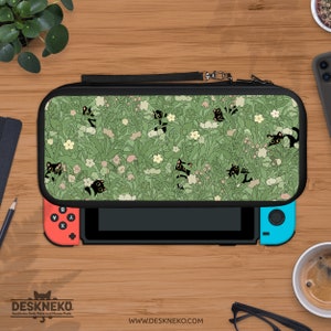 Pode incluir: Uma capa de transporte preta e verde para Nintendo Switch com um padrão de gatos pretos entre flores e folhagens. A capa está aberta, revelando os controles Joy-Con vermelhos e azuis. A marca "DESKNEKO" é visível na parte inferior.