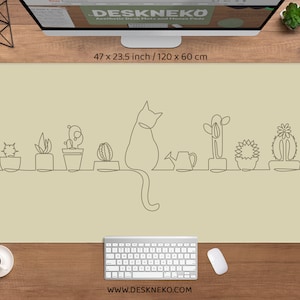 May include: A beige desk mat with a continuous line drawing of a cat and potted cacti. The mat is 47 x 23.5 inches (120 x 60 cm). A computer, keyboard, mouse, and coffee cup are on a wooden desk.
