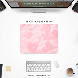May include: A pink desk mat with a cloud and celestial design, measuring 18 x 14 inches. The mat features white outlines of moons, stars, suns, and planets. The website address www.deskneko.com is printed at the bottom.