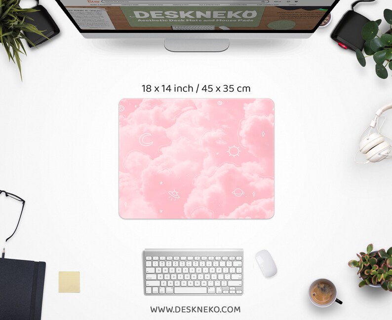May include: A pink desk mat with a cloud and celestial design, measuring 18 x 14 inches. The mat features white outlines of moons, stars, suns, and planets. The website address www.deskneko.com is printed at the bottom.
