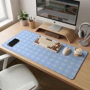 Könnte beinhalten: Hellblaue Schreibtischunterlage mit weißem Herz- und Quadratmuster. Eine cremefarbene Tastatur mit braunen Tastenkappen, eine kabellose Maus und ein Smartphone liegen auf der Unterlage. Ein Computermonitor und eine Kaffeetasse sind ebenfalls zu sehen.