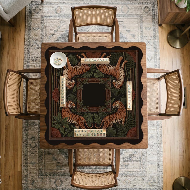 May include: A square wooden mahjong table with a decorative playing surface featuring tigers and foliage. The table is surrounded by four cane-backed chairs. A small white bowl and mahjong tiles are on the table.