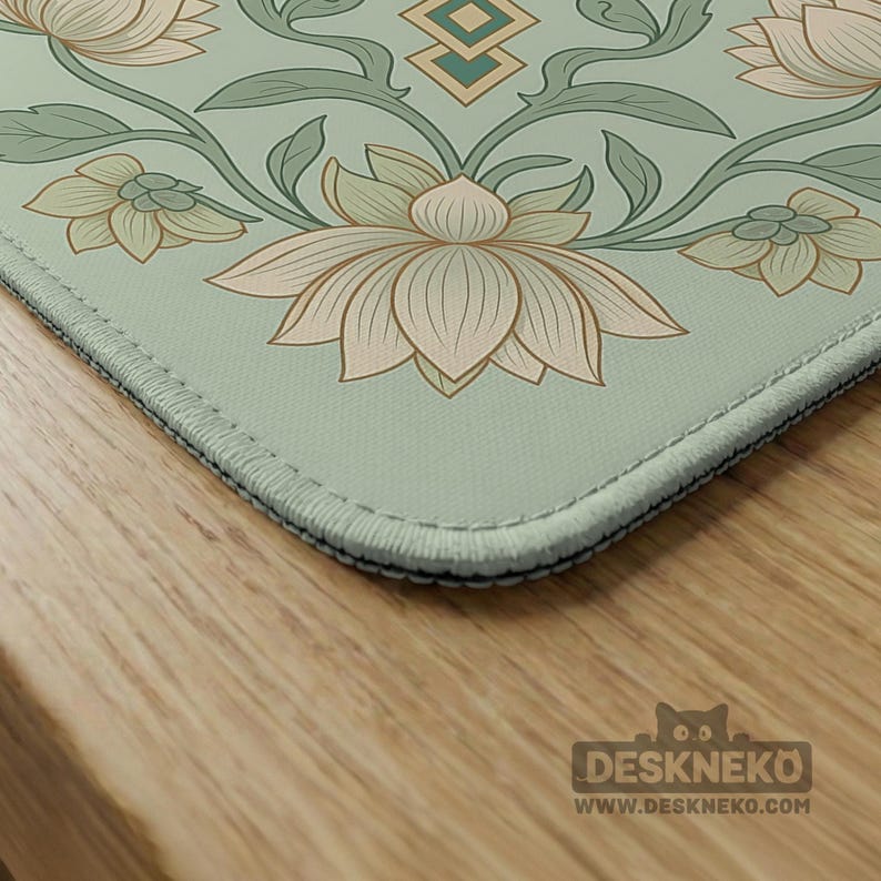 May include: A rectangular desk mat featuring a light sage green background with a repeating floral pattern of cream-colored lotus flowers and dark green stems. The mat has stitched edges and includes the text DESKNEKO and WWW.DESKNEKO.COM.