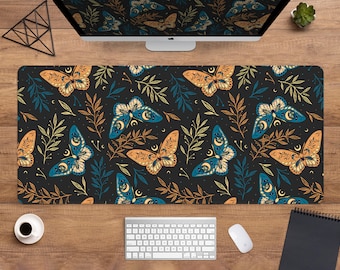 Peut inclure: Tapis de bureau rectangulaire noir avec un motif répété de papillons de nuit et de feuillage dans des tons de bleu, orange et or. Les papillons de nuit ont des détails de croissant de lune. Un ordinateur, un clavier, une souris et une tasse de café sont visibles.
