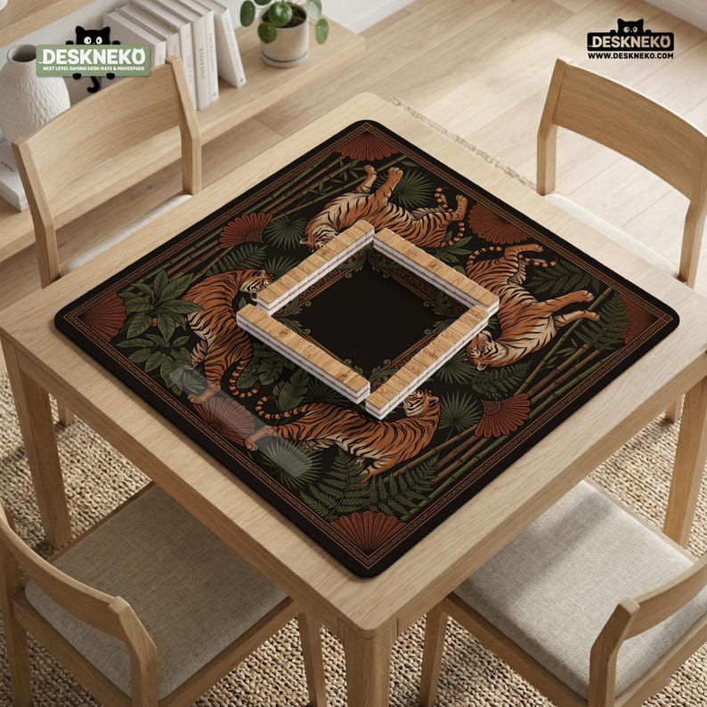 May include: A square desk mat featuring a tiger and foliage design in shades of orange, brown, and green. The mat has a black center and a wooden frame. The mat is on a wooden table with chairs.