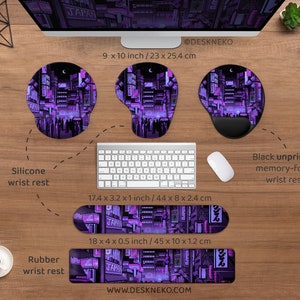 K&ouml;nnte beinhalten: Ein Schreibtisch-Setup mit Tastatur, Maus und Handgelenkauflagen. Die Handgelenkauflagen zeigen ein lila-schwarzes Stadtbild-Design mit japanischem Text. Die Silikon-Handgelenkauflage misst 23 x 25,4 cm. Die Gummi-Handgelenkauflage misst 45 x 10 x 1,2 cm.