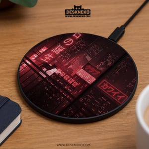 Puede incluir: Un cargador inalámbrico negro con un diseño de paisaje urbano rojo y negro. El cargador presenta texto japonés y una silueta de gato. La marca "DESKNEKO" está impresa en la parte superior.