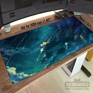 May include: A large rectangular desk mat with a celestial design. The mat features a dark blue and teal sky with white clouds and shooting stars. The mat is 47 inches long and 23.5 inches wide, with the text "Up to 120 cm / 47" and "60cm / 23.5" printed on it.