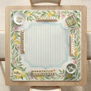 May include: A wooden Mahjong table with a light blue and white striped center. The table is decorated with a lemon and floral design. Small bowls with game pieces and tiles are placed on the table. The logo "DESKNEKO" is visible.