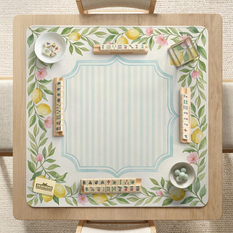 May include: A wooden Mahjong table with a light blue and white striped center. The table is decorated with a lemon and floral design. Small bowls with game pieces and tiles are placed on the table. The logo "DESKNEKO" is visible.