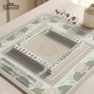 May include: A beige and green Mahjong set arranged on a matching mat. The mat features a lotus flower design and a central circular pattern. The Mahjong tiles are white with black and red markings. The logo "DESKNEKO" is visible in the top left corner.