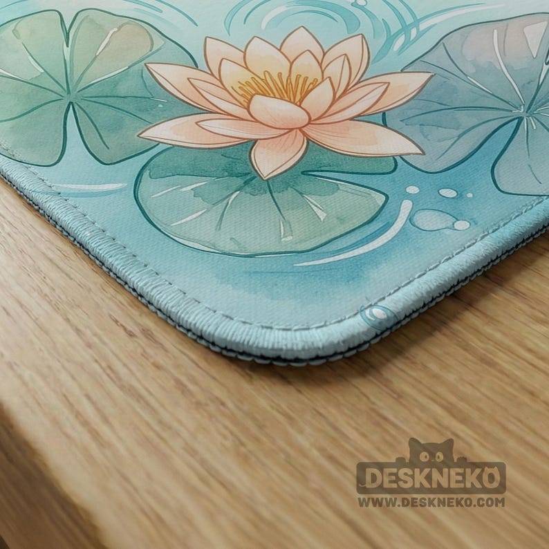May include: A rectangular desk mat featuring a watercolor illustration of a light peach lotus flower surrounded by green lily pads on a light blue water surface with ripples. The bottom right corner displays the text DESKNEKO WWW.DESKNEKO.COM.