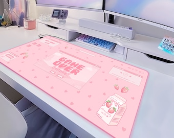May include: Pink rectangular desk mat with a strawberry milk carton illustration and the text "GAME OVER". The mat features a repeating heart pattern and other graphic elements. A fun and decorative accessory for a computer desk.