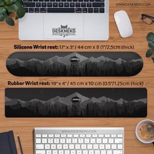 May include: Two wrist rests with a mountain and forest design. The silicone wrist rest is 17" x 3" and the rubber wrist rest is 18" x 4". Both are black and gray with a watchtower in the center. The brand name is Deskneko.