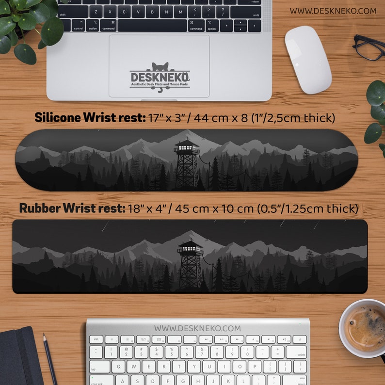 May include: Two wrist rests with a mountain and forest design. The silicone wrist rest is 17" x 3" and the rubber wrist rest is 18" x 4". Both are black and gray with a watchtower in the center. The brand name is Deskneko.