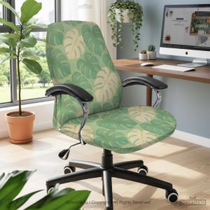 May include: An office chair with a green and cream monstera leaf pattern. The chair has black armrests and a black base with wheels. The background includes a desk, a computer, and plants.