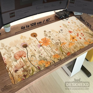 Puede incluir: Una alfombrilla de escritorio rectangular con un diseño floral con flores naranjas, amarillas y beige. La alfombrilla mide hasta 120 cm de largo y 60 cm de ancho. El texto "Up to 120 cm / 47" está impreso en la alfombrilla. La dirección del sitio web también está impresa.