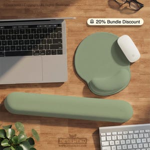 May include: A sage green ergonomic mouse mat with a wrist rest, a matching wrist rest, and a white mouse are displayed on a wooden desk. A laptop and keyboard are also visible. The image includes the text "20% Bundle Discount".