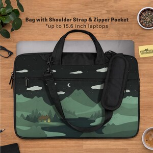May include: Black laptop bag with a landscape design featuring mountains, trees, and a house under a night sky. Includes a shoulder strap, zipper pocket, and the text "Bag with Shoulder Strap & Zipper Pocket *up to 15.6 inch laptops".