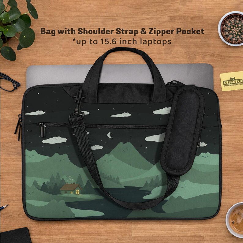 May include: Black laptop bag with a landscape design featuring mountains, trees, and a house under a night sky. Includes a shoulder strap, zipper pocket, and the text "Bag with Shoulder Strap & Zipper Pocket *up to 15.6 inch laptops".