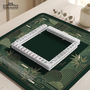 Pode incluir: Um conjunto de Mahjong com pe&ccedil;as brancas e marca&ccedil;&otilde;es vermelhas e verdes &eacute; disposto sobre um tapete verde escuro com um desenho de bambu e nuvens. O tapete tem um centro verde escuro e uma borda verde mais clara. O logotipo "DESKNEKO" e o endere&ccedil;o do site est&atilde;o no canto superior esquerdo.