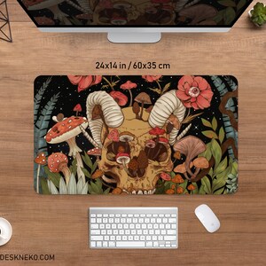 Może przedstawiać: Prostokątna podkładka na biurko z motywem czaszki i grzyb&oacute;w, o wymiarach 60 x 35 cm. Podkładka przedstawia czaszkę z rogami, otoczoną przez r&oacute;żne grzyby i kwiaty. Tło jest czarne z gwiazdami, a podkładka ma tekst "DESKNEKO".