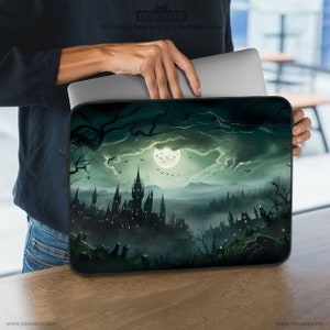 May include: A laptop sleeve featuring a dark, gothic castle scene under a full moon. The design includes silhouetted trees, bats, and a misty landscape in shades of green and black. The text "DESKNEKO" is visible.