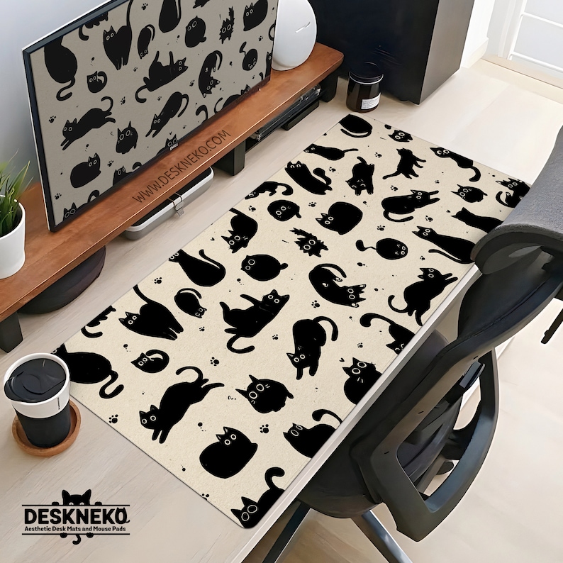 Puede incluir: Una alfombrilla de escritorio beige con un patr&oacute;n repetido de siluetas de gatos negros en varias poses. La alfombrilla tiene el texto "DESKNEKO" y "Aesthetic Desk Mats and Mouse Pads" en la parte inferior, y "WWW.DESKNEKO.COM" en el soporte del monitor. La alfombrilla es rectangular.