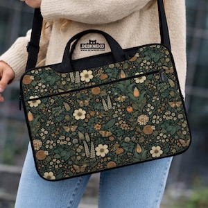 May include: Black laptop bag with a floral pattern in shades of green, beige, and brown. The bag features a zipper closure, a top handle, and a shoulder strap. The text "DESKNEKO" is printed on the top of the bag.