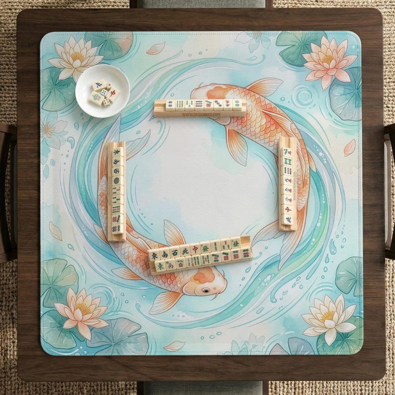 K&ouml;nnte beinhalten: Eine quadratische Mahjong-Matte mit hellblauem Wasserhintergrund, zwei orangefarbenen Koi-Fischen in einer Kreisbewegung, umgeben von rosa Lotusbl&uuml;ten und gr&uuml;nen Seerosenbl&auml;ttern. Vier Holzst&auml;nder halten Mahjong-Steine und eine kleine wei&szlig;e Schale enth&auml;lt W&uuml;rfel.