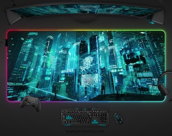 May include: A large rectangular gaming mouse mat with a vibrant cityscape design in teal and blue. The mat has a colourful LED edge and features a keyboard, mouse, and game controller. The website address deskneko.com is visible.