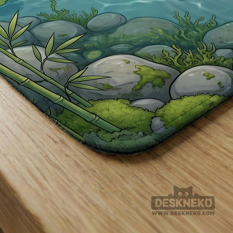 May include: A rectangular desk mat featuring a digital illustration of a tranquil stream bed with smooth grey river stones, patches of vibrant green moss, and green bamboo stalks. The bottom right corner displays the text DESKNEKO WWW.DESKNEKO.COM.