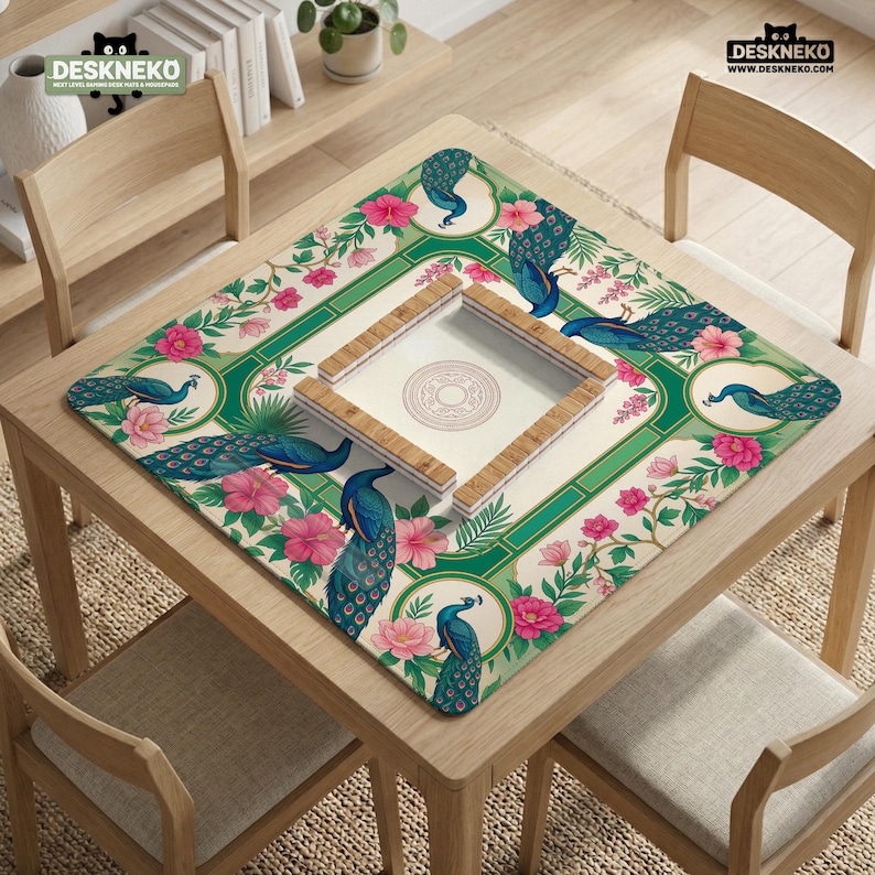 May include: A square mahjong mat featuring a cream background with a green border, decorated with blue peacock illustrations and pink hibiscus flowers. In the center, a wooden mahjong tile tray holds tiles with a circular emblem design.