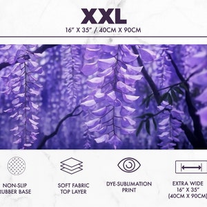May include: XXL mousepad featuring a vibrant purple wisteria design. The extra wide mat measures 16" x 35" and has a non-slip rubber base and soft fabric top layer. The dye-sublimation print showcases the floral artwork.