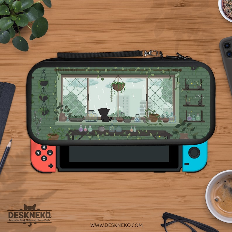 May include: Black Nintendo Switch case with a pixel art design of a cat gazing out of a window at a rainy scene. The case has a black handle and zip. The Switch has red and blue controllers. The website address is visible.