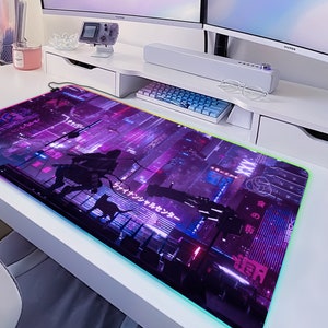 May include: A rectangular gaming mouse pad with a vibrant, neon-lit cityscape design in shades of purple and blue. The pad features a silhouette of a figure and a cat, with Japanese text. The edges are illuminated with a colorful LED light.