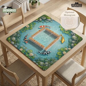 May include: A square desk mat featuring a pond scene with koi fish, lily pads, and rocks surrounding a central wooden frame graphic. The design includes a circular inset showing an optional monogram with the letters YM. The mat has a smooth surface.