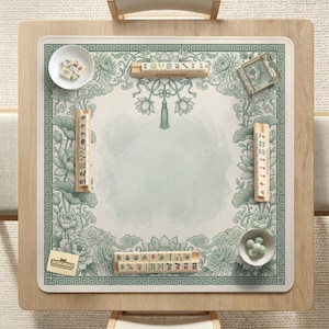 Puede incluir: Una mesa de mahjong cuadrada de madera con una estera de dise&ntilde;o floral verde y blanco. La estera presenta un borde decorativo, detalles florales y un &aacute;rea central para jugar. Varias fichas de mahjong, cuencos y un peque&ntilde;o recipiente de vidrio est&aacute;n dispuestos en la estera.