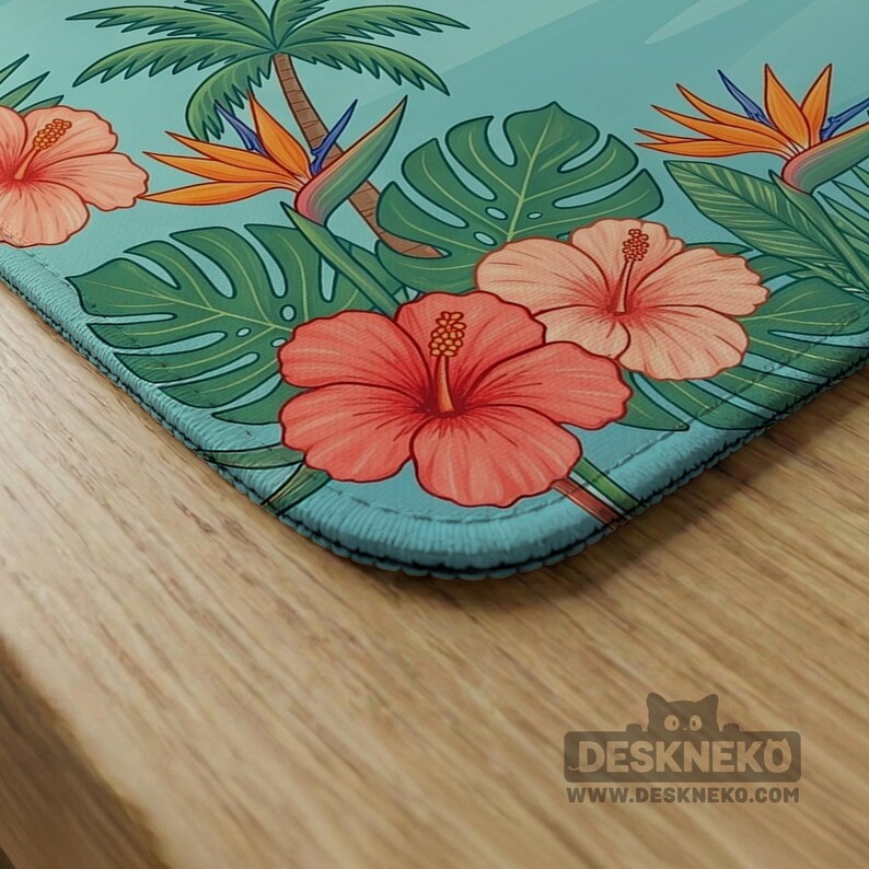May include: A rectangular desk mat with a light blue background featuring a tropical pattern of pink hibiscus flowers, orange bird of paradise flowers, green monstera leaves, and palm trees. The text DESKNEKO WWW.DESKNEKO.COM is printed in the corner.