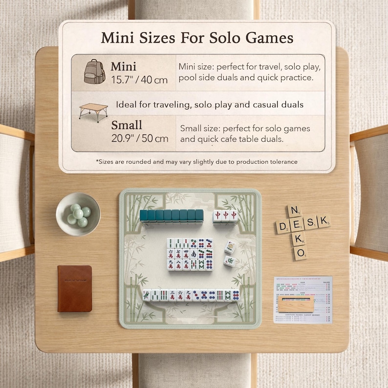 May include: A Mahjong set on a light wood table with a game mat featuring bamboo illustrations. Includes a small bowl of green marbles, a brown notebook, a wooden tile rack, and a score sheet. A sign displays Mini Sizes For Solo Games with 15.7 inch and 20.9 inch options.