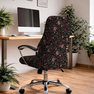May include: An office chair featuring a black fabric upholstery with a dense floral pattern of red and pink roses and green leaves. The chair has a chrome metal base with five wheels, black armrests, and a height-adjustable swivel mechanism.